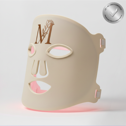 GlowWithin™ LED face mask in ivory with rose-gold “M” logo and soft red light glow, credibility badge in corner
